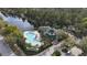 Aerial view of community pool, clubhouse, green roof, and palm trees near a lake at 3050 Pirates Retreat Ct # 402, Kissimmee, FL 34747