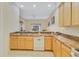 Kitchen with wooden cabinetry, double stainless sink, white dishwasher, and stone-look countertops at 3050 Pirates Retreat Ct # 402, Kissimmee, FL 34747