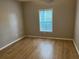 A bright bedroom with hardwood flooring and a window overlooking a treed backyard at 3561 Conroy Rd # 214, Orlando, FL 32839