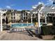 Community pool with covered seating, decorative planters, and lounge chairs under a blue sky at 3561 Conroy Rd # 214, Orlando, FL 32839