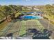 Aerial view of two well-maintained tennis courts, a pool, clubhouse, and a scenic pond in a lush community at 4353 Shadow Crest Pl # 3, Orlando, FL 32811