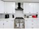 Close up of a modern kitchen showcasing white cabinets, subway tile backsplash, and a range hood at 458 Hollinghead Loop, Davenport, FL 33896