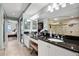 Bathroom with dual sinks, black granite countertops, vanity area, walk-in shower, and access to bedroom at 4651 S Atlantic Ave # 2030, Ponce Inlet, FL 32127