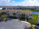 Aerial shot of a two-story condo building near a pond, featuring a tile roof, parking lot, and manicured landscaping at 4841 Romeo Cir, Kissimmee, FL 34746
