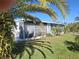 Charming exterior featuring an enclosed porch, well-manicured lawn, and lush palm trees in a serene setting at 50989 Highway 27 # 130, Davenport, FL 33897