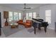 Spacious living room featuring a curved sofa, piano, and ample natural light through large windows at 528 Lobelia Dr, Lake Mary, FL 32746