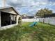 View of the fenced in backyard with a green lawn, screened in patio, and swing set at 536 Dunoon St, Ocoee, FL 34761