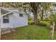 Back view of a home in a serene backyard setting with lush grass and mature trees at 5569 Jessamine Ln, Orlando, FL 32839