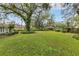 Expansive backyard with lush green lawn and mature trees, offering ample space for outdoor activities at 5569 Jessamine Ln, Orlando, FL 32839