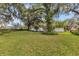 A serene backyard with mature trees, lush green grass, and a view of the fence-enclosed yard at 5569 Jessamine Ln, Orlando, FL 32839