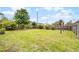 A well-maintained backyard with a lush green lawn, surrounded by a wooden fence and shady trees at 864 Naples Dr, Orlando, FL 32804