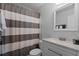 Bathroom featuring striped shower curtain, grey vanity with white countertop and a decorative mirror at 864 Naples Dr, Orlando, FL 32804