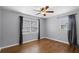 Bedroom with two windows, hardwood floors, neutral walls, dark curtains and a ceiling fan with lighting at 864 Naples Dr, Orlando, FL 32804