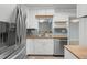 Modern kitchen featuring stainless steel appliances, white cabinetry, light blue backsplash and wood countertops at 864 Naples Dr, Orlando, FL 32804