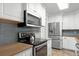 Well-equipped kitchen featuring stainless steel appliances, white cabinets, wood countertops, and backsplash at 864 Naples Dr, Orlando, FL 32804