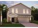 Two-story home showing the front door, two-car garage, a paved driveway, and a palm tree in the front yard at 872 Scrub Oak Hammock Rd, Davenport, FL 33837