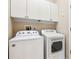 Bright laundry room with front loading washer and dryer and white cabinets above at 892 Cool Springs Cir, Ocoee, FL 34761