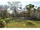 Lush backyard featuring a wooden pergola with a table and bench, shaded by mature trees, and a storage shed at 933 Lakehurst St, Lakeland, FL 33805