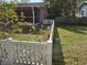 Backyard with a white picket fence, green grass, and mature trees, offering privacy and a serene outdoor space at 933 Lakehurst St, Lakeland, FL 33805