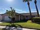 Beautiful front exterior with lush green lawn, palm trees and tile roof at 10753 Wilderness Ct, Orlando, FL 32821