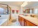 Bathroom features double vanity, wood cabinets, framed mirror, step in shower and soaking tub at 11604 Acosta Ave, Orlando, FL 32836