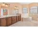 Bathroom with a large tub and a double vanity with marble counters and warm peach-colored walls at 12018 Se 175Th Loop, Summerfield, FL 34491