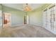 Empty main bedroom with light green walls, three windows, carpet flooring and two access doors at 12018 Se 175Th Loop, Summerfield, FL 34491