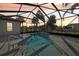 Screened-in pool area with a built-in spa, surrounded by lush landscaping and a beautiful sunset view at 12018 Se 175Th Loop, Summerfield, FL 34491