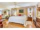 Spacious bedroom featuring a bed, a ceiling fan, mirrored closet, and hardwood floors at 1226 E Schwartz E Blvd, Lady Lake, FL 32159