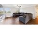 Spacious living room featuring dark wood floors, a ceiling fan, and a comfortable gray sectional sofa at 128 Calabria Springs Cv, Sanford, FL 32771