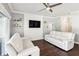 Modern living room with a ceiling fan, flat-screen TV, built in shelving and white sofas at 128 Calabria Springs Cv, Sanford, FL 32771