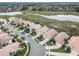 A high-angle view of houses situated along a peaceful street, with scenic water and a treeline in the distance at 13336 Lake Turnberry Cir, Orlando, FL 32828