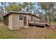 Back exterior view of home, featuring a wood deck, tan siding, and a lush green yard with mature trees at 14226 Nell Dr, Orlando, FL 32832