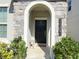 Stylish home entryway featuring a stone archway, a Hello mat, and well-maintained landscaping at 15127 Book Club Rd, Winter Garden, FL 34787