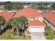 Aerial view of a two-story home with a red tile roof, palm trees, a well-manicured lawn, and a two-car garage at 1520 Solana Cir, Davenport, FL 33897