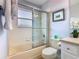 Bright bathroom featuring a shower over tub with glass sliding doors and neutral tile at 1520 Solana Cir, Davenport, FL 33897