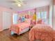 Pink bedroom with two beds, princess wall art, and wood-look laminate flooring at 1520 Solana Cir, Davenport, FL 33897