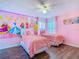 Pink bedroom with two beds, princess wall art, and wood-look laminate flooring at 1520 Solana Cir, Davenport, FL 33897