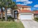 Two-story stucco home featuring an attached two-car garage, tile roof, and manicured front lawn at 1520 Solana Cir, Davenport, FL 33897