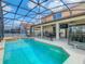 Sparkling pool with a safety fence and covered patio and outdoor kitchen areas are visible in this backyard at 1520 Solana Cir, Davenport, FL 33897