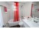 Bathroom featuring tub, white marble-look tile, vanity, and striking red window curtain at 1721 Sandalwood Sw Cir, Winter Haven, FL 33880