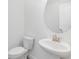 Powder room with a pedestal sink, toilet, and round mirror at 18441 Mowry Ct, Orlando, FL 32827