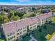 Low-angle aerial view of yellow apartment buildings with well-maintained lawns and mature trees under a clear blue sky at 2019 Dixie Belle Dr # 2019W, Orlando, FL 32812