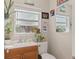 A cozy bathroom with a white toilet and a sink with wooden cabinets and decorations at 210 N East St, Maitland, FL 32751