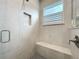 Close up of a tiled shower with a window and a built-in seat in a modern bathroom at 2348 Clemblue Rd, Clermont, FL 34715