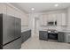 A bright kitchen featuring stainless steel appliances, gray lower cabinets, and stylish white countertops at 3000 Stonington Run, Kissimmee, FL 34746