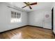 Simple bedroom with hardwood floors, white walls, ceiling fan, and a window for natural light at 303 S Forest Ave, Orlando, FL 32803