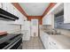 Galley kitchen featuring white cabinets and appliances, stainless steel range, and tiled floors at 303 S Forest Ave, Orlando, FL 32803