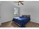 Bedroom with a bed dressed in blue, wood-look floors, ceiling fan, and bright window at 3443 Players Point Loop, Apopka, FL 32712