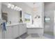 Bright bathroom featuring double sinks, white cabinets, tub, walk in shower and decorative chandelier at 4068 Stone Creek Loop, Lake Wales, FL 33859